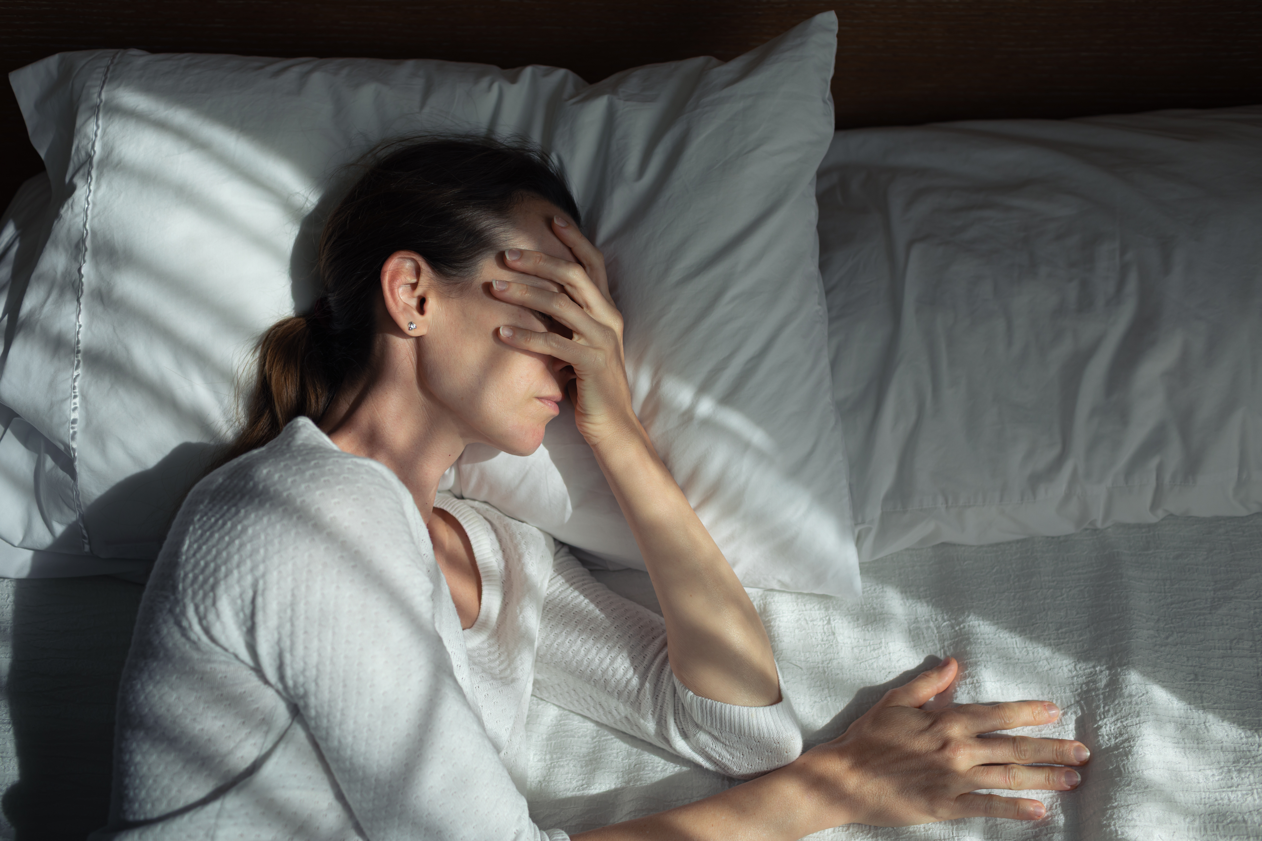 femme souffrant de migraine au lit