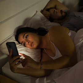 Femme au lit utilisant son téléphone